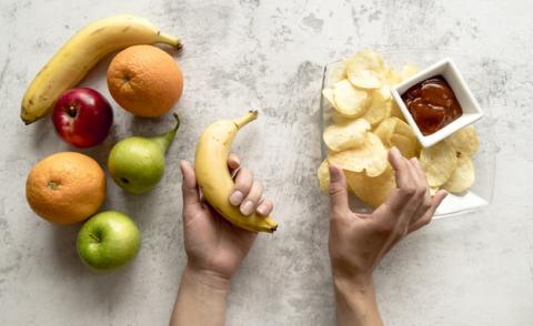 human-hand-holding-banana-potato-chips-cement-surface_23-2148193100.jpg